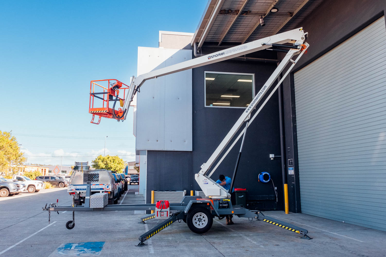 Snorkel TL37J trailer-mounted boom lift raised beside a commercial building