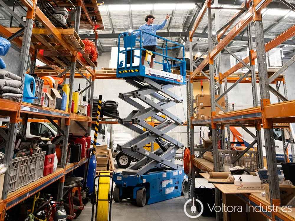 Genie GS-2632 electric scissor lift raised with operator on platform